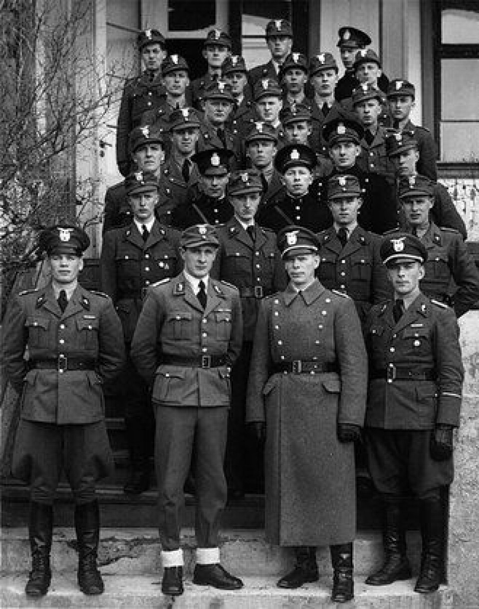 Statspolitiet: Bestod av deler av den opprinnelige politistyrken, innblandet med over mange rekruttert til politiet av Gestapo. Her en gruppe politimenn og lensmannsbetjenter avbildet etter tilbakekomst fra Berlin i 1942. Nye og gamle uniformer ble brukt om hverandre og vanlige politiluer side om side med militære vinterluer. Kilde: Boken «Mellom barken og veden
