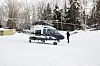 Politihelikopter fra Helikoptertjenesten står parkert i snø med tjenesteperson ved siden av.