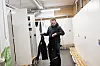 Mann i garderobe holder politiuniform foran åpne skap og trebenker.