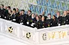 En gruppe uniformerte kadetter står på en hvit balkong med dekorative gulldetaljer og blomster.