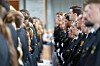 To rekker med uniformerte personer står vendt mot hverandre i en lys innendørs gang.