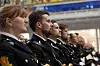 En rekke uniformerte personer sitter side om side i en stor hall under en seremoni.