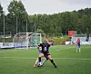 To fotballspillere kjemper om ballen nær mål på en utendørs bane.