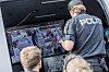 Politifolk ser på flere skjermer med kart og videobilder inne i en operasjonsbil.