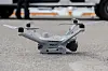 En grå politimerket drone står på asfalt med fire armer og kamera.